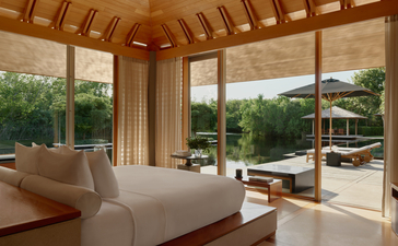 アマンヤラのトランキリティ・ヴィラの寝室。床から天井までの窓から庭園と海の景色が見えます。