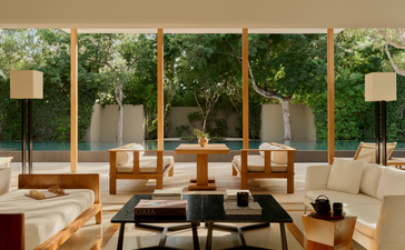 Two-bedroom pool villa lounge at Amanyara with floor-to-ceiling windows overlooking tropical gardens.