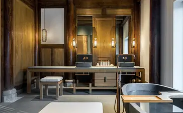 Antique villa bathroom at Amanyangyun with wooden cabinetry, dual sinks, and warm lighting.