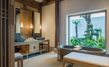 Antique-style bathroom at Amanyangyun with dual vanity, dark wooden beams, and garden views through window.