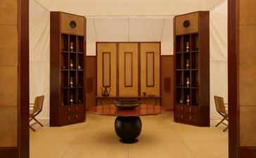 Symmetrical dining tent interior at Aman-i-Khas with wooden doors, built-in shelving, and central seating arrangement.
