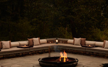 Curved seating arrangement around a central fire pit at Aman-i-Khas, India, at dusk.