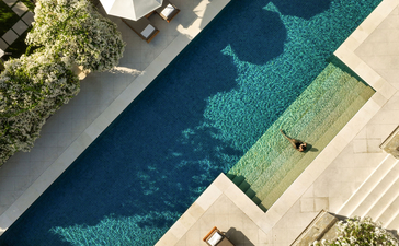 Aerial view of a resort swimming pool at Aman Villas at Nusa Dua, Indonesia, with turquoise water and surrounding terraces.