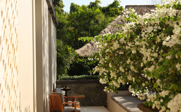 Resort terrace at Aman Villas at Nusa Dua with wooden chair and lush garden views.