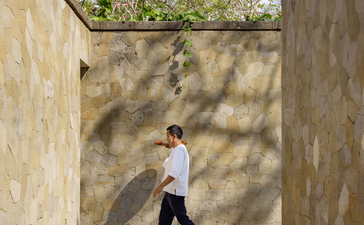 Private butler walking through shaded courtyard at Aman Villas at Nusa Dua, Indonesia.