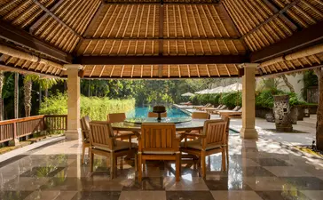 Dining pavilion at Aman Villas at Nusa Dua, with wooden teak ceiling, table seating, and ocean views.