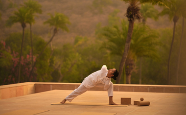 Woman practising yoga in a wellness pavilion at Amanbagh, India, with painted desert landscape backdrop.