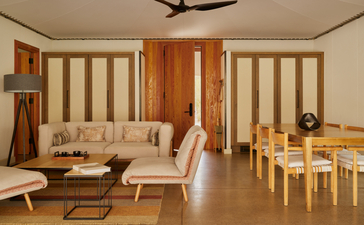 Pavillon d'hébergement spacieux à Amangiri avec salon meublé simplement et salle à manger, murs couleur crème et boiseries chaudes.