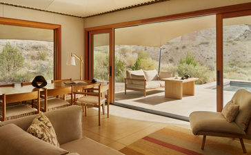 Pavillon d'hébergement Sarika avec salon spacieux et baies vitrées donnant sur le paysage désertique d'Amangiri.