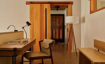 Pavillon d'hébergement Sarika à Amangiri, avec bureau en bois, chaise et porte d'entrée.