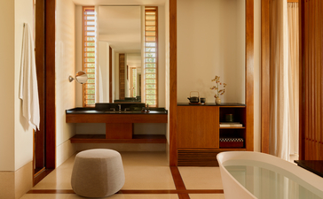 アマンヤラ リゾートのオーシャン コーヴ パビリオンの、木製の家具と鏡を備えた広々とした室内スペース。