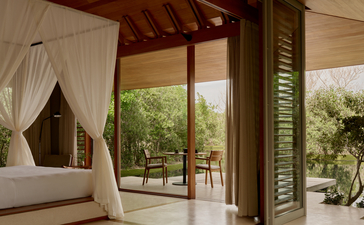 Tranquility Pavilion bedroom at Amanyara with canopied bed and views to terrace beyond.