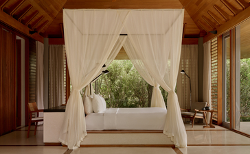 Tranquility Pavilion at Amanyara with draped four-poster bed and ocean views through open windows.