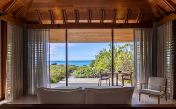 Ocean Cove Pavilion principal bedroom with wooden ceiling, sheer curtains, and views towards the Turks and Caicos coastline.
