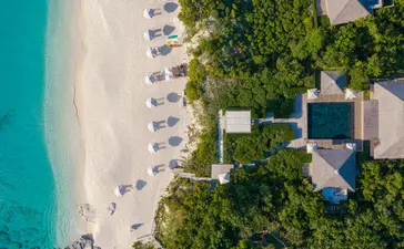 Aerial view of a four-bedroom beach sala villa at Amanyara, Turks and Caicos, with turquoise waters and white sand.