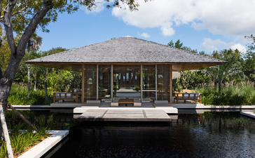 安缦涯澜度假村的四卧海滨别墅外观，木制结构建筑坐落于水畔，周围环绕热带植被。