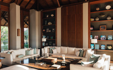 安缦涯澜度假村四卧海滨沙龙别墅的宽敞室内空间，采用温暖木质调和米色家具。