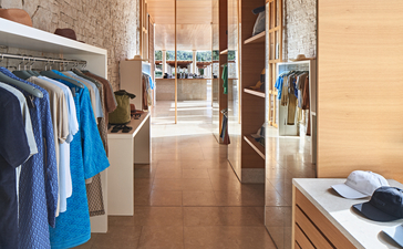 Corridor at Amanzoe resort with wooden flooring and clothing displayed on wall-mounted rails.