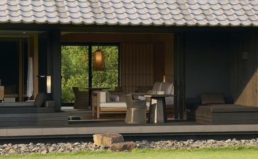 Amanemu resort pavilion with wooden deck, open doors, and minimalist furnishings overlooking gardens.