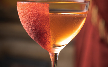 アマン ヴェニスのバーで提供されるシグネチャーカクテル「デヴォツィオーネ」の詳細。琥珀色の液体にグレープフルーツスライスが飾られたカクテル。