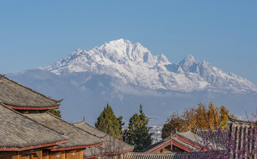 Snow-capped mountain rising above traditional wooden structures at Amandayan in spring.