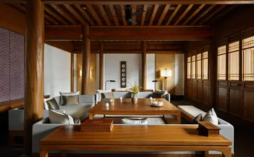大研安缦度假村宽敞的起居区，木质天花板和隔断营造温暖氛围，自然光线洒入室内。