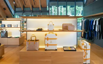 Aman Essentials boutique at Amanpuri resort, featuring wooden shelving and displays with folded garments and products.