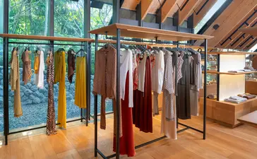 Aman Essentials boutique at Amanpuri resort displaying colourful textiles and garments on wooden rails.