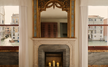 Chambre avec cheminée et miroir doré au-dessus, Aman Venice.