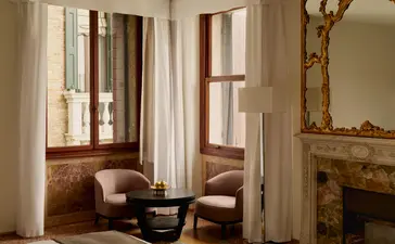 Palazzo room at Aman Venice hotel with classical venetian architecture, tall windows overlooking the Grand Canal, and period furnishings.
