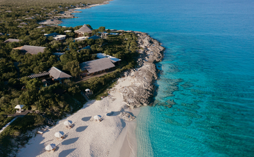 Aerial view of Amanyara resort's sandy beach curving along turquoise waters in Turks and Caicos.