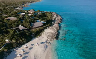 Aerial view of Amanyara resort's sandy beach curving along turquoise waters in Turks and Caicos.