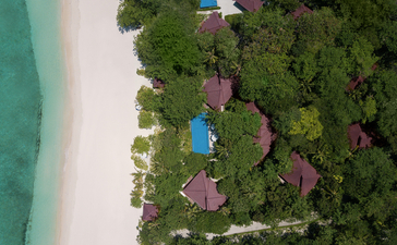 Aerial view of a beachfront villa nestled among tropical vegetation at Amanpulo resort, with turquoise waters and white sand beach.
