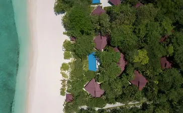 Vue aérienne d'une villa avec piscine privée entourée de végétation tropicale et de plage blanche à Amanpulo.