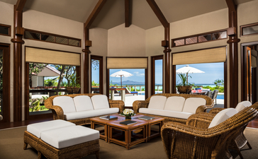 Airy villa interior at Amanpulo resort with expansive sea views through floor-to-ceiling windows and natural wooden furnishings.