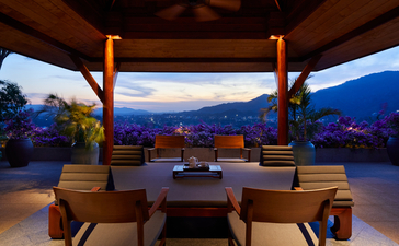 Amanpuri seven-bedroom ocean villa lounge at dusk, with wooden ceiling beams framing views of the Andaman Sea.