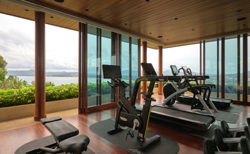 Amanpuri villa gym with exercise equipment overlooking Thai countryside.