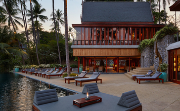 Eight-bedroom ocean villa terrace at Amanpuri, with loungers facing the sea and palm trees beyond.