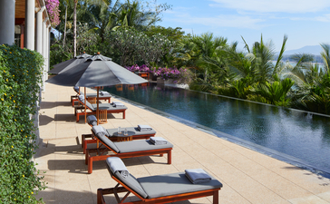 アマンプリのリゾートにある、七寝室のオーシャンヴィラのスイミングプール、ビーチラウンジャーと川の景色。