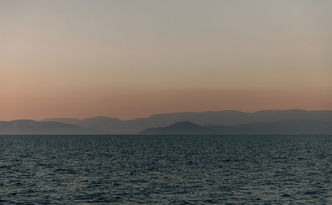 Calm waters at dusk with distant mountains silhouetted against a soft sky at Amanruya.