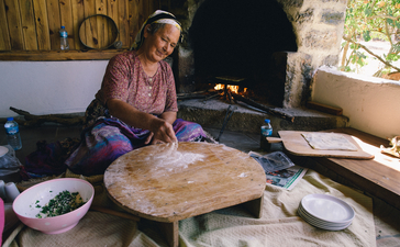 Woman preparing traditional Turkish bread on a wooden board at Amanruya.