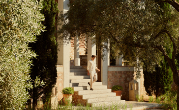 Amanruya's main residence illuminated at dusk, framed by olive trees.