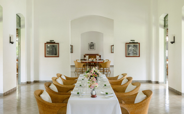 Dining hall at Amantaka with long table, wooden chairs, and arched ceiling.