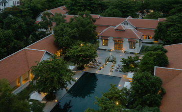 Aerial view of Amantaka's terracotta-roofed pavilions surrounding a central plunge pool, nestled amongst lush greenery.