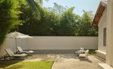 Amantaka Khan Pool Suite exterior with sun loungers on terrace beside lawn and pool wall.