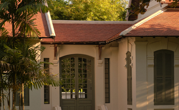 Khan Pool Suite entrance at Amantaka, featuring terracotta roof and stone exterior among lush gardens.