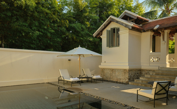 Outdoor terrace with swimming pool at Amantaka, Laos, featuring cream pavilion and loungers.