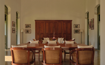 Amantaka's meetings room with wooden desk, leather chairs and framed artwork on pale walls.