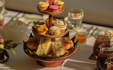 Afternoon tea tiered stand with pastries and cakes in the library at Amantaka, Laos.