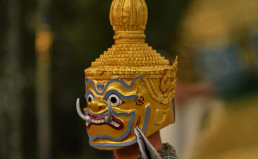 Close-up of a gilded Lao masked dance drama figure at Amantaka's poolside dinner performance.